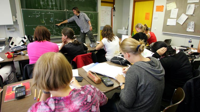Beim Physikunterricht an einer Freiburger Schule erklärt ein Lehrer seiner Klasse an der Tafel Formeln (Archivbild).  (Foto: dpa Bildfunk, picture alliance / dpa | Patrick Seeger)