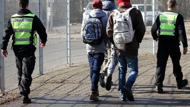 Mitarbeiter einer Sicherheitsfirma begleiten auf dem Gelände der Erstaufnahmestelle in Sigmaringen eine Gruppe von Asylbewerbern (Archivbild).