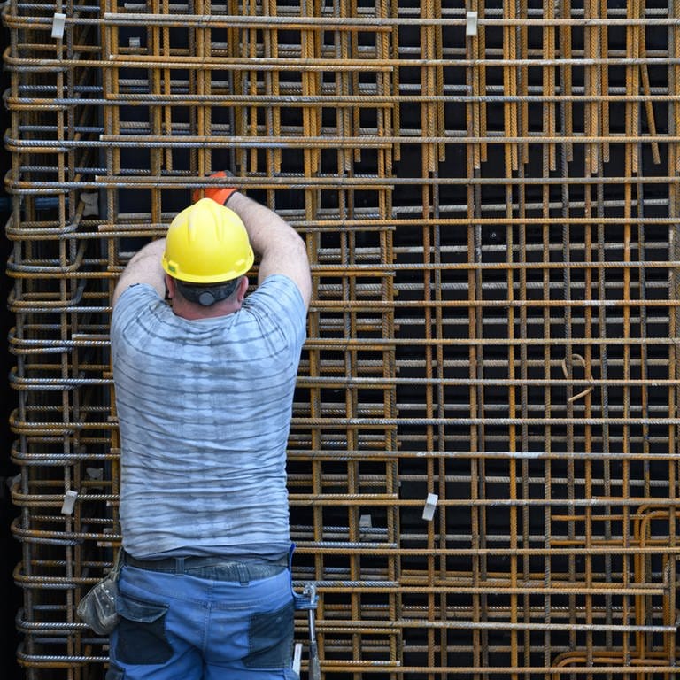 Ein Bauarbeiter beschäftigt sich auf einer Baustelle mit einer Stahlbetonwand.  (Foto: dpa Bildfunk, picture alliance/dpa | Robert Michael)