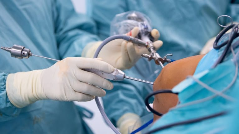 Ein Arzt operiert einen Patienten am Knie (Symbolbild).