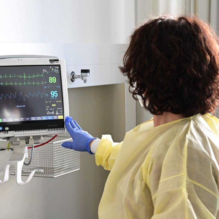 Eine Pflegerin schaut in einem Krankenzimmer im Klinikum Stuttgart auf einen Monitor einer Patientin.