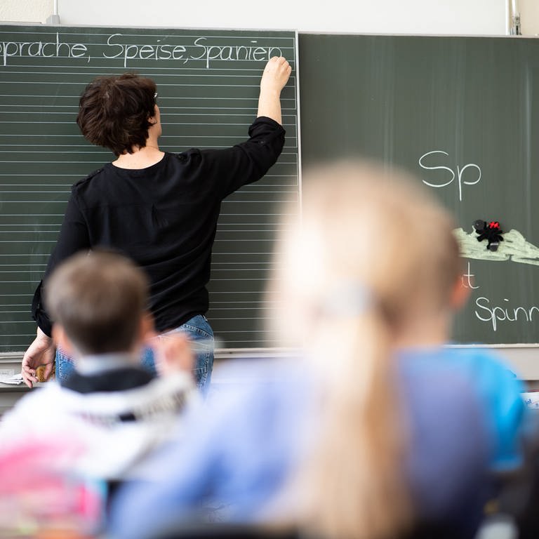 Eine Lehrerin schreibt in einer Grundschule Wörter mit "Sp" am Anfang an eine Tafel.  (Foto: dpa Bildfunk, Picture Alliance)