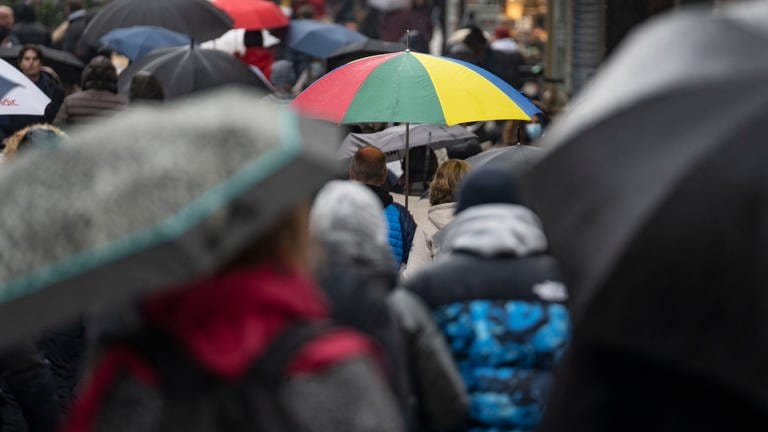 Passanten mit Schirmen bevökern bei grauem und nassem Wetter eine Straße der Fußgängerzone in der Innenstadt.  (Foto: dpa Bildfunk, picture alliance/dpa | Frank Rumpenhorst)