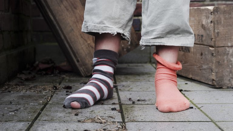 Ein zehn Jahre altes Mädchen steht in abgetragener Kleidung ohne Schuhe in einem Hinterhof. (Foto: dpa Bildfunk, picture alliance/dpa | Christian Hager)