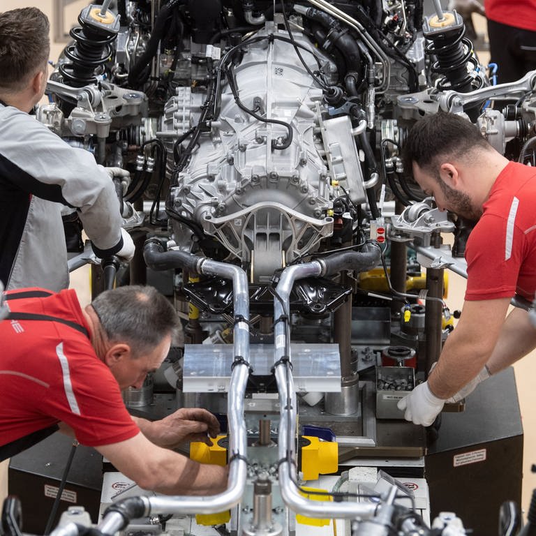 Mitarbeiter der Porsche AG montieren im Hauptwerk den Motor eines Porsche 911. Auto- und Zulieferindustrie: Von gefährdeten Jobs hin zu neuen Berufen