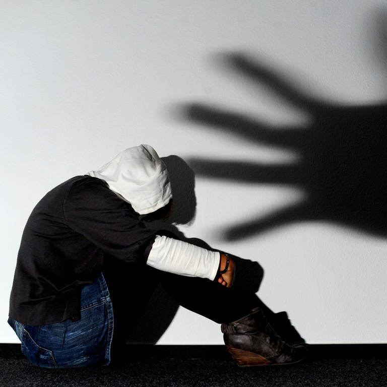 Ein Mädchen sitzt am Mittwoch (14.09.2011) vor einer Wand, auf der der Schatten einer Hand groß zu sehen ist (Foto: dpa Bildfunk, Picture Alliance)