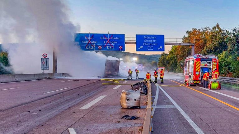 Unfall auf der A5 bei Karlsruhe: ausgebrannter Lkw liegt auf der Fahrbahn, Feuerwehrleute bei Löscharbeiten (Foto: ER24 / FW Ettlingen / EinsatzReport24)