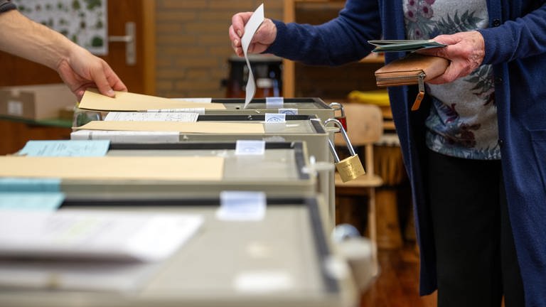 Ein Frau wirft in Bayern bei der Landtagswahl ihren Stimmzettel in die Wahlurne. 