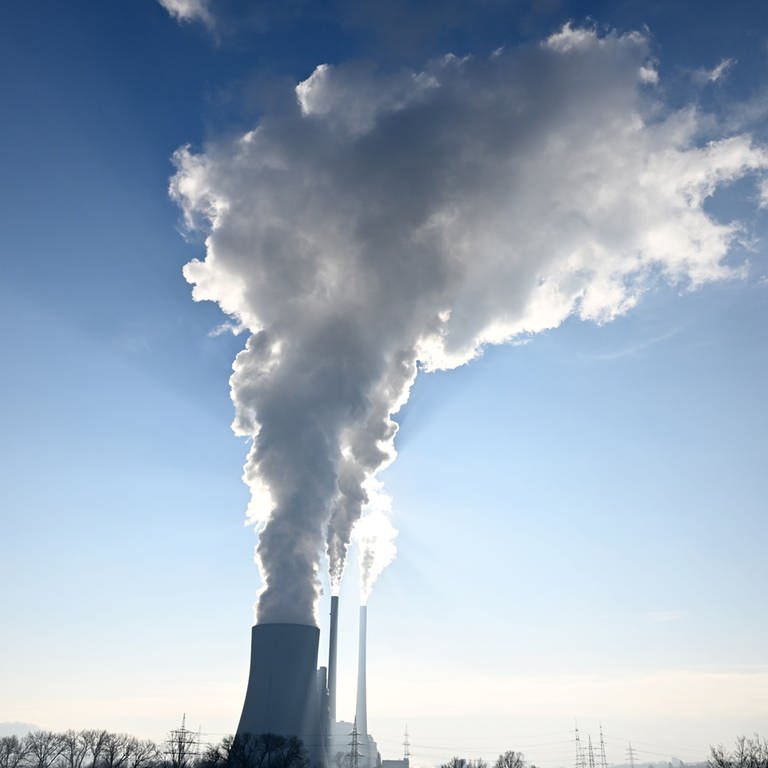 Wolken aus dem Kühlturm und den Schornsteinen des Kohlekraftwerks bei Neckarsulm werden von der Sonne angestrahlt.