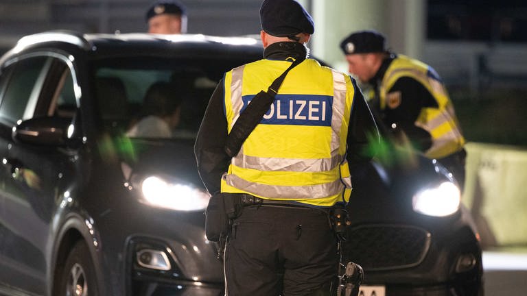 Polizisten kontrollieren an der Grenze zu Deutschland Autos. 