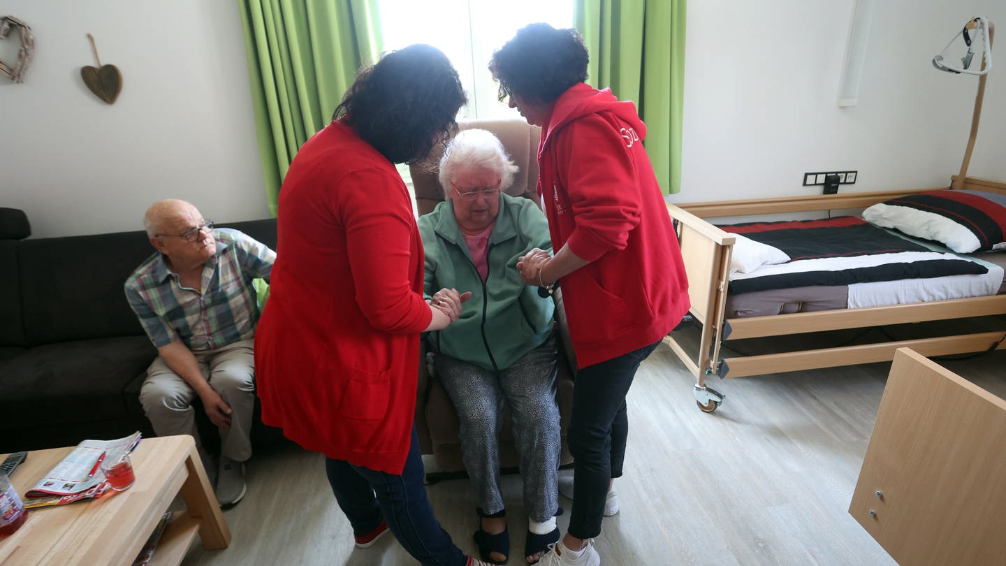 Pflegekräfte helfen einer pflegebedürftigen Frau aufzustehen. (Foto: dpa Bildfunk, picture alliance/dpa | Karl-Josef Hildenbrand)