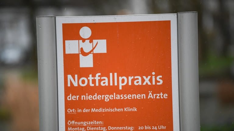 Ein Schild mit der Aufschrift "Notfallpraxis der niedergelassenen Ärzte" steht vor einem Gebäude an der Universitätsklinik Freiburg.