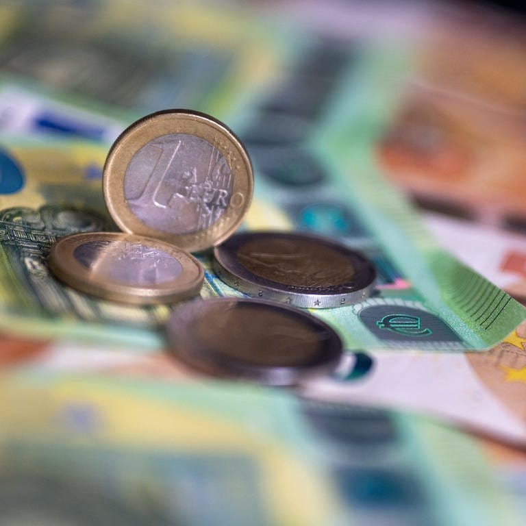 Geldscheine mit dem Wert von 100 und 50 Euro und Münzen liegen auf einem Tisch. Viele Versicherungen 2024 werden teurer. (Foto: dpa Bildfunk, picture alliance/dpa | Monika Skolimowska)