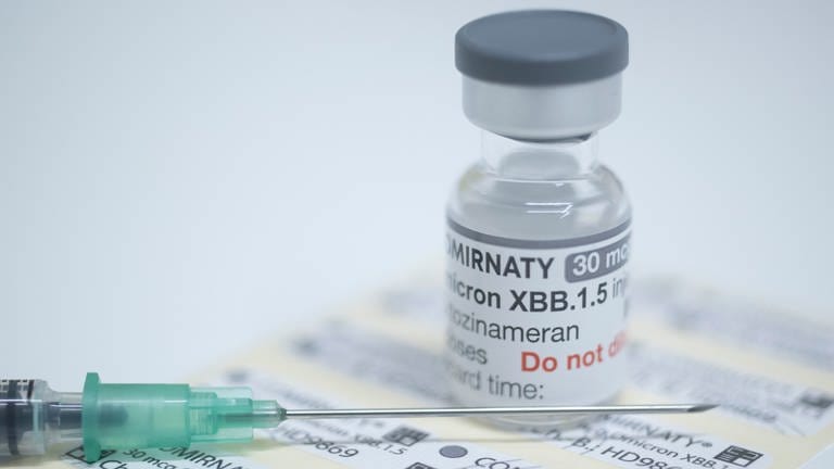 Eine Ampulle mit 6 Dosen des neuen an die Omikron-Sublinie XBB.1.5 angepassten Corona-Impfstoffs steht auf einem Tisch in einer Apotheke.