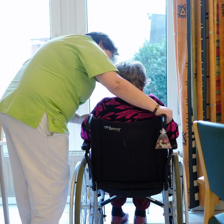 Pflegerin beugt sich über Frau in Rollstuhl (Foto: dpa Bildfunk, Picture Alliance)