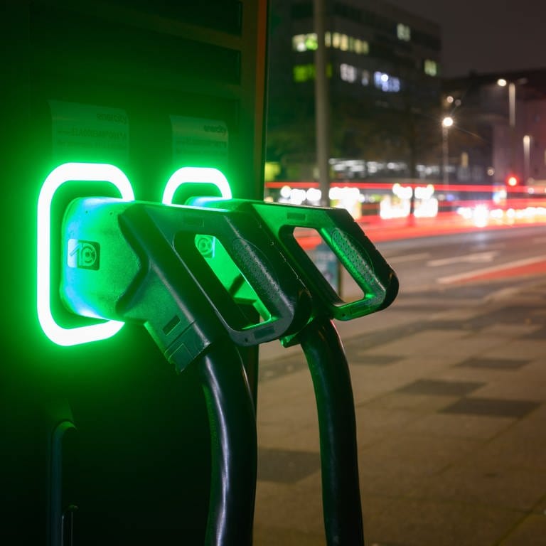 Grün leuchten Ladekabel an einer Schnellladesäule für Elektroautos.