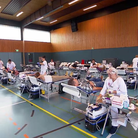 Menschen spenden Blut in einer Turnhalle