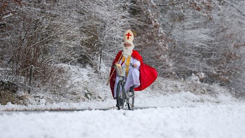 Ein Mann will trotz Schneewetter mit dem Fahrrad auf eine Kostümfeier gelangen (Foto: dpa Bildfunk, Picture Alliance)