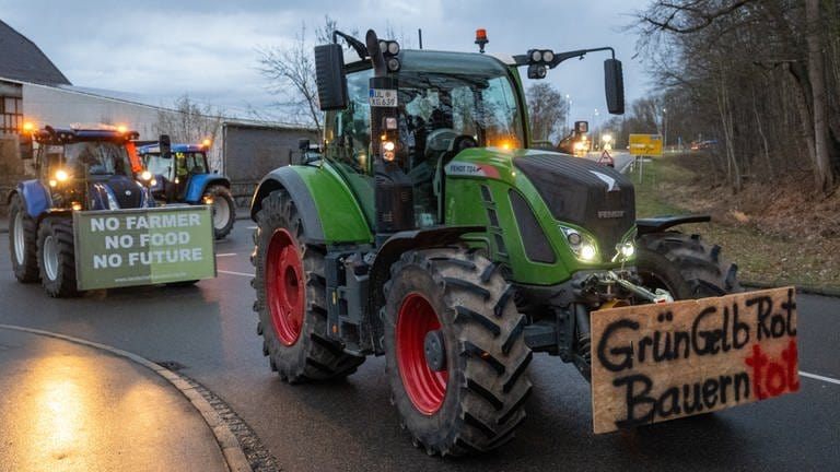 Landwirte fahren im Konvoi durch die Stadt, auf einem Plakat steht "GrünGelbRot Bauern tot".