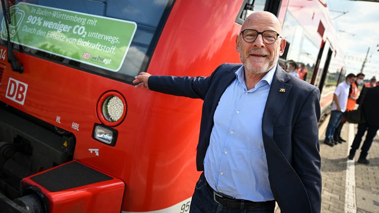 Winfried Hermann, Verkehrsminister von Baden-Württemberg, steht neben dem Regionalzug, der als bundesweit erster mit Biokraftstoff betankt werden soll.