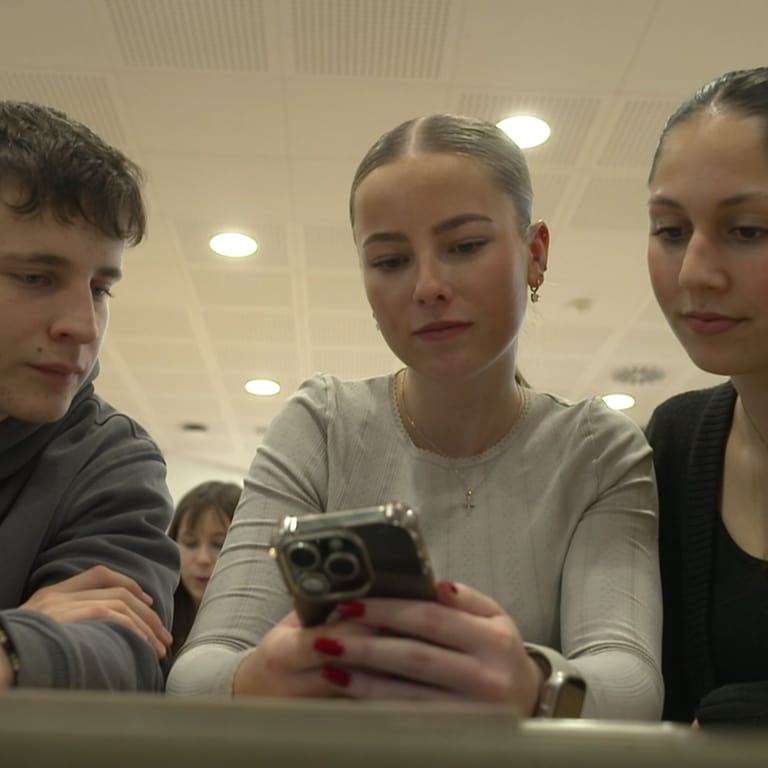 Drei Schüler schauen auf ein Smartphone. (Foto: SWR)