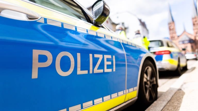 Zwei Einsatzfahrzeuge der Polizei stehen in Freiburg am Straßenrand.