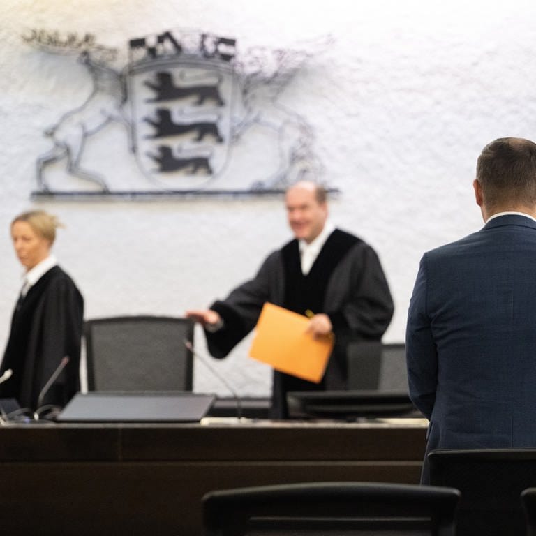 Anton Baron (vorne), Fraktionsvorsitzender der AfD im Landtag von Baden-Württemberg, steht vor einer Urteilsverkündung des Verfassungsgerichtshofs Baden-Württemberg in einem Gerichtssaal.