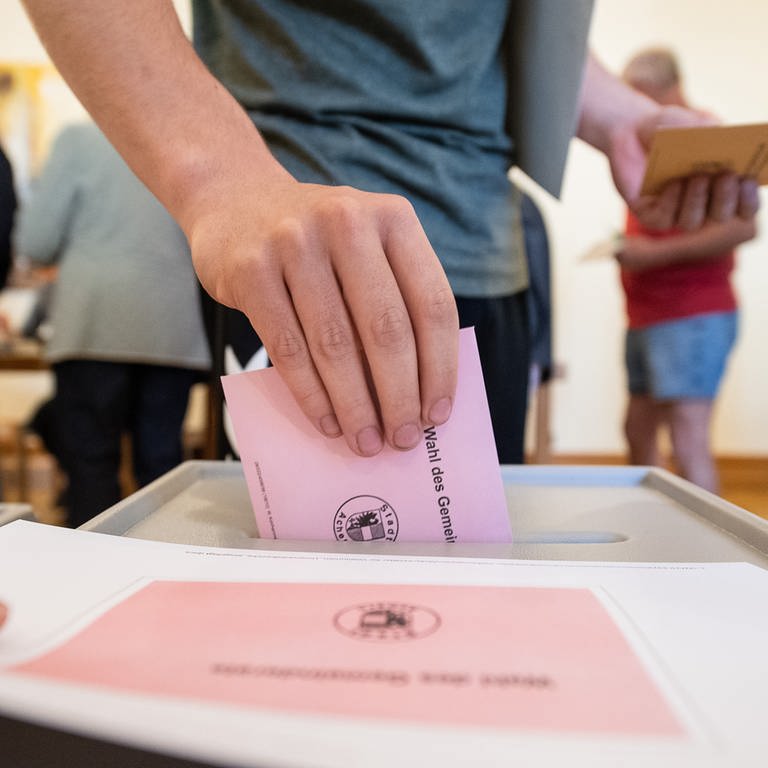 Symbolbild: Ein Mann wirft seinen Stimmzettel für die Kommunalwahl in Baden-Württemberg ein. 