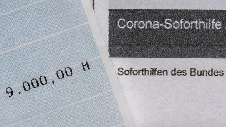 Ein Kontoauszug mit der überwiesenen Summe von 9.000 Euro Corona-Soforthilfe liegt auf einem Antrag für den Zuschuss.
