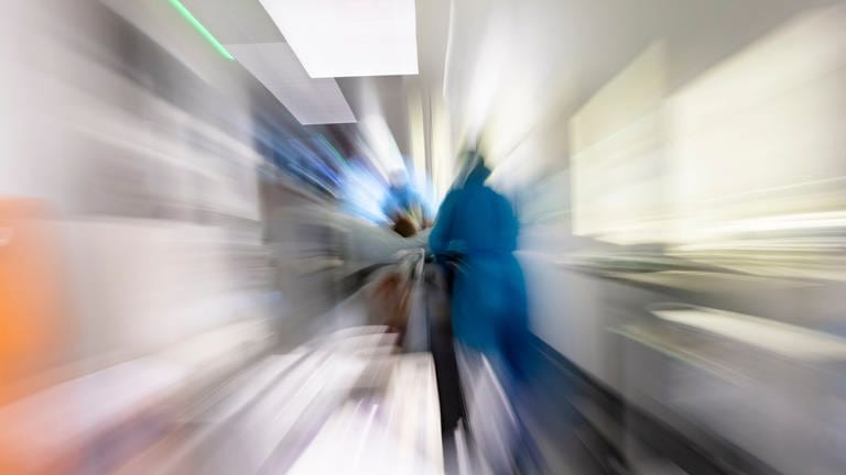 Symbolbild: Eine Krankenpflegerin schiebt ein Krankenbett durch einen Krankenhausflur.