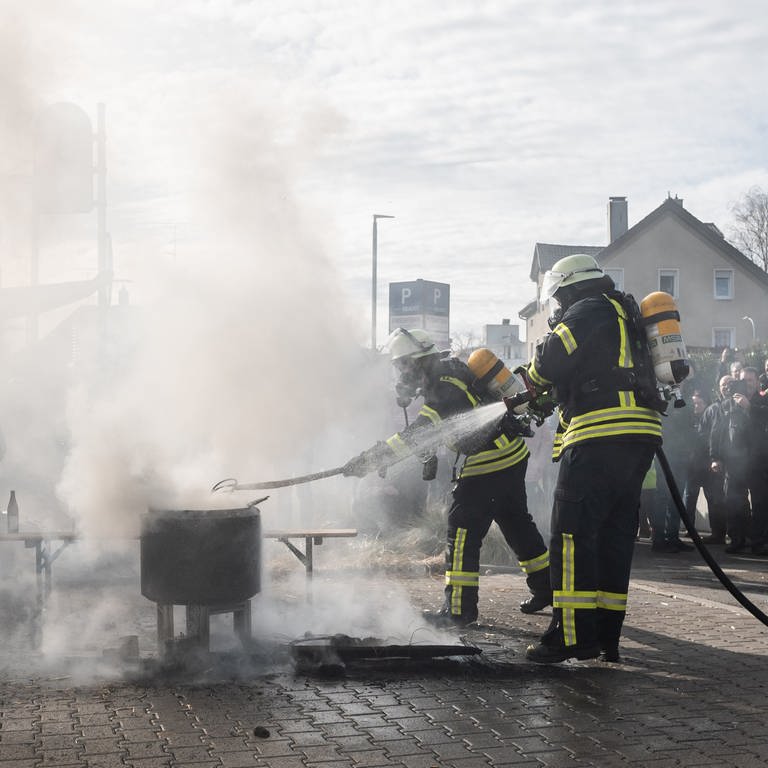 Feuerwehrleute löschen am Mittwoch (14.02.) ein Feuer von Demonstrierenden.