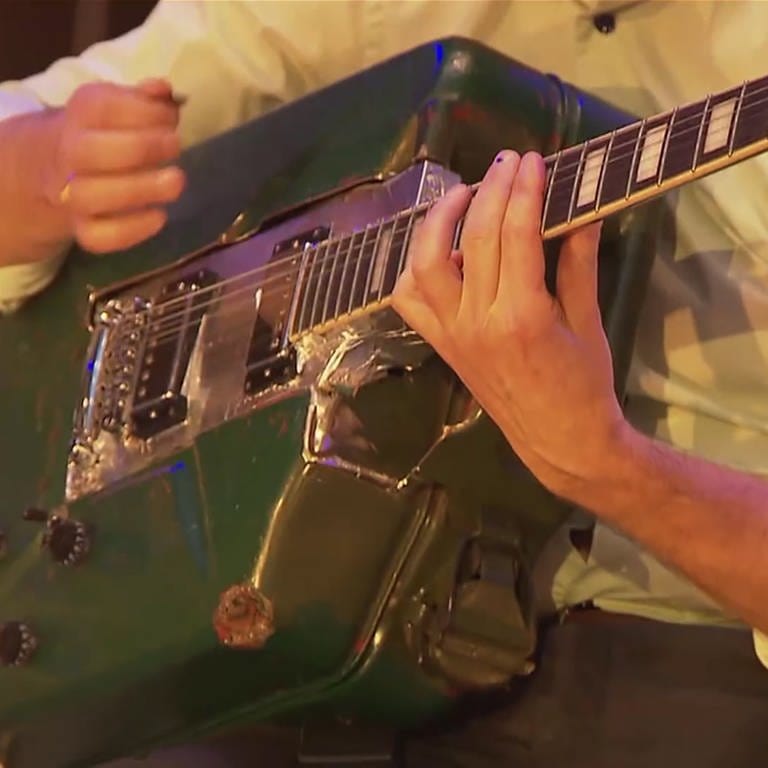 Mann spielt auf der aus einem Benzinkanister gebauten Gitarre