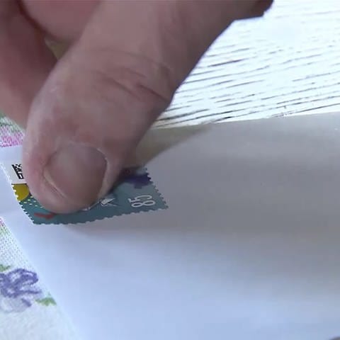 Briefmarke wird auf einen Briefumschlag aufgeklebt (Foto: SWR)