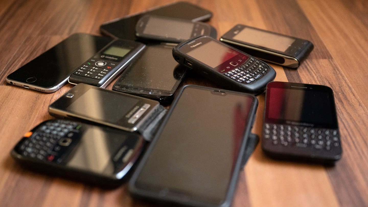 Alte Handys und Smartphones liegen auf einem Tisch. Schätzungsweise rund 210 Millionen Altgeräte werden in Schubladen und Schränken in Deutschland gehortet. (Foto: dpa Bildfunk, picture alliance/dpa | Lisa Ducret)