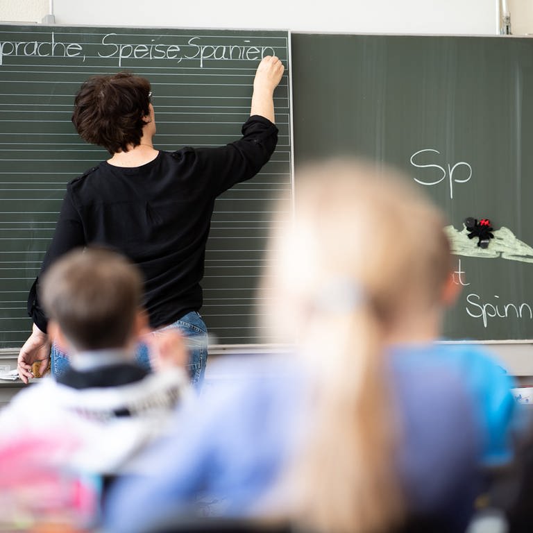 Eine Lehrerin schreibt in einer Grundschule Wörter mit "Sp" am Anfang an eine Tafel.  (Foto: dpa Bildfunk, picture alliance/dpa | Sebastian Gollnow)