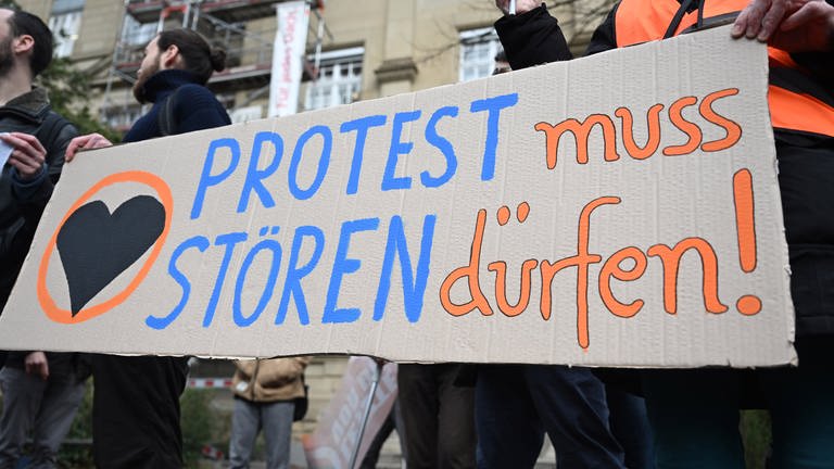 Klimaaktivisten der "Letzten Generation" protestieren vor dem Oberlandesgericht (OLG) Karlsruhe mit einem Plakat auf dem steht "Protest muss stören dürfen!".  (Foto: dpa Bildfunk, picture alliance/dpa | Uli Deck)