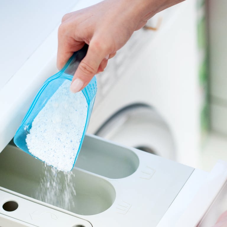 Waschpulver wird in das Waschmittelfach einer Waschmaschine eingefüllt.