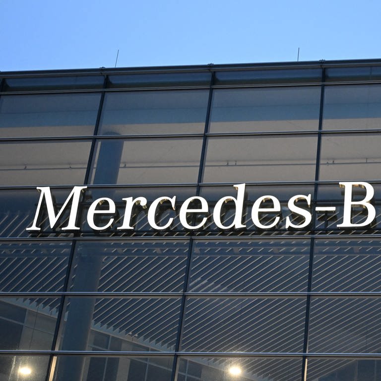 Ein Schriftzug des Automobilherstellers Mercedes-Benz an der Fassade eines Bürogebäudes.