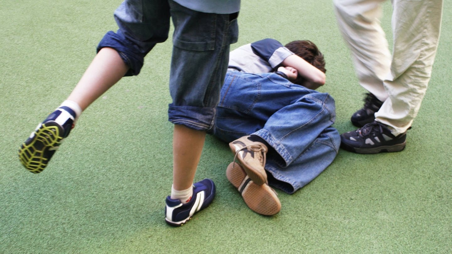 Ein Schüler tritt auf einen am Boden liegenden ein. (Foto: IMAGO, IMAGO/serienlicht (Symbolbild))