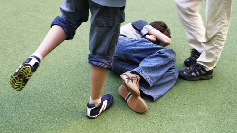 Ein Schüler tritt auf einen am Boden liegenden ein.