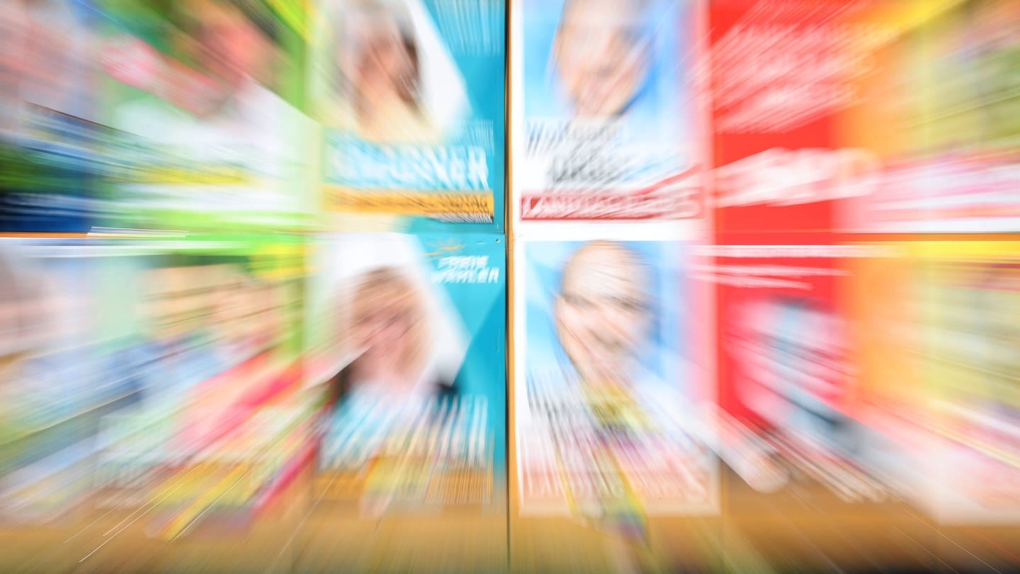 Eine Plakatwand zeigt verschwommen Plakate verschiedener Parteien zur bayerischen Landtagswahl 2023. (Foto: dpa Bildfunk, picture alliance/dpa | Karl-Josef Hildenbrand)