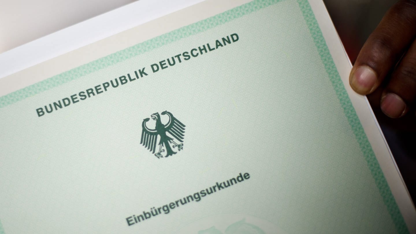 Ein Mann hält eine Einbürgerungsurkunde der Bundesrepublik Deutschland in der Hand. (Foto: dpa Bildfunk, Foto: Julian Stratenschulte)
