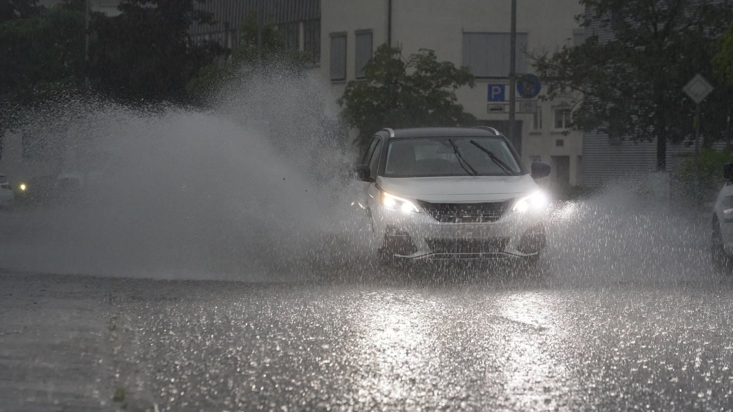 EIn Auto fährt bei Starkregen über eine regennasse Straße. (Foto: dpa Bildfunk, Picture Alliance)