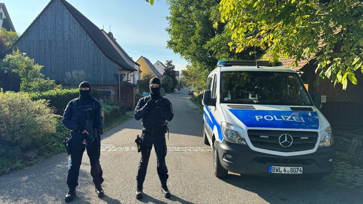 Zwei Polizisten des SEK stehen neben einem Polizeiauto im Ortsteil Hesselbronn. (Foto: dpa Bildfunk, Picture Alliance)