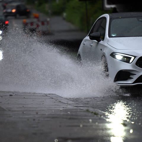 Ein Auto fährt durch eine große Wasserlache.