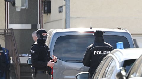Zwei SEK-Einsatzkräfte stehen an Autos in Reutlingen.