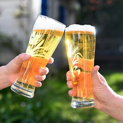 Zwei Personen stoßen mit Biergläsern an. 
