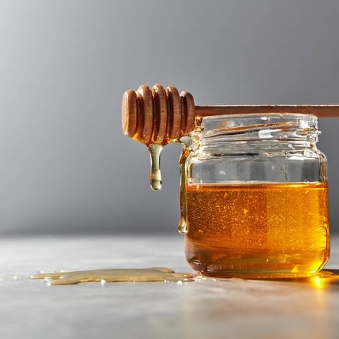Honig tropft an einem Glas herunter.