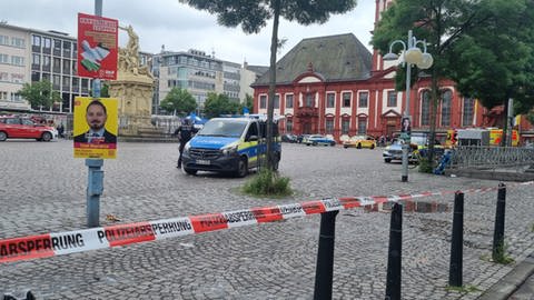 Ein Polizeiauto steht hinter Absperrband auf dem Marktplatz in Mannheim.