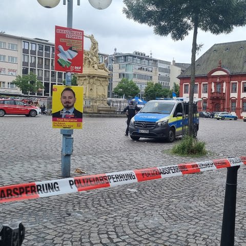 Ein Polizeiauto steht hinter Absperrband auf dem Marktplatz in Mannheim.